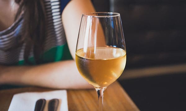 a glass of wine next to a woman