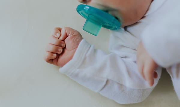 premature baby sleeping in a crib with a pacifier