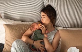 woman holding baby while resting during her sitting month